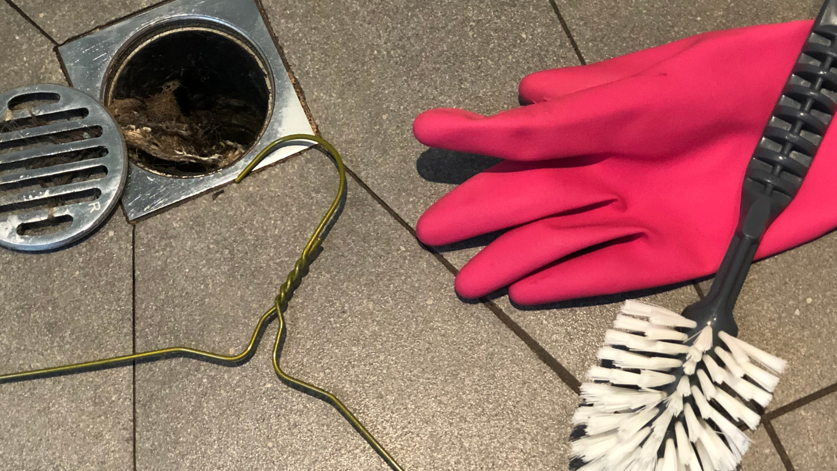 a shower drain with buildup and cleaning tools